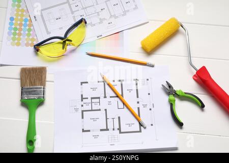 Designer's workplace with color palettes, floor plans and different supplies on white wooden table, flat lay Stock Photo