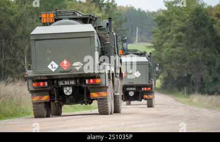 convoy of British army Heavy Utility Trucks driving along a dirt track road, Wilts UK Stock Photo