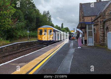 Northern rail class 769 bi-mode train 769458 arriving at Gathurst railway station   with motion blur and morning commuters waiting on the platform Stock Photo