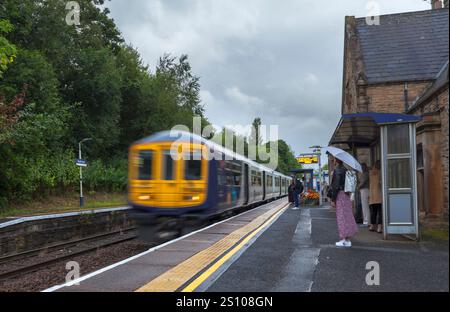 Northern rail class 769 bi-mode train 769458 arriving at Gathurst railway station   with motion blur and morning commuters waiting on the platform Stock Photo