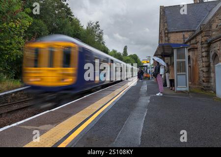 Northern rail class 769 bi-mode train 769458 arriving at Gathurst railway station   with motion blur and morning commuters waiting on the platform Stock Photo