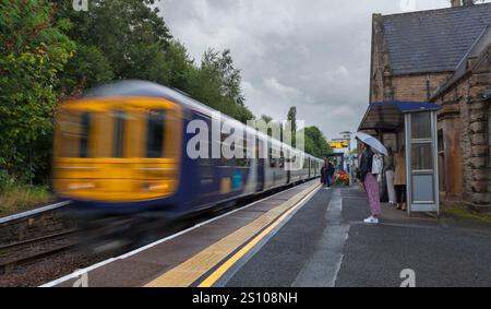 Northern rail class 769 bi-mode train 769458 arriving at Gathurst railway station   with motion blur and morning commuters waiting on the platform Stock Photo