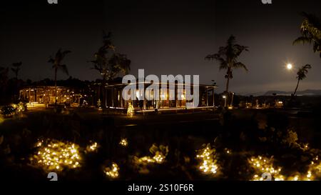 Tropical resort at night with illuminated bungalows and palm trees under moonlight. Stock Photo