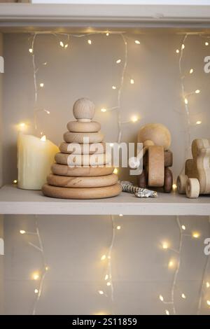 A wooden toy car is on a shelf next to a stack of wooden blocks. The blocks are stacked in a pyramid shape Stock Photo