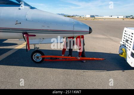 Tug driver pushing a plane to its parking spot with two other men walking as safety guides for wingtip clearance Stock Photo