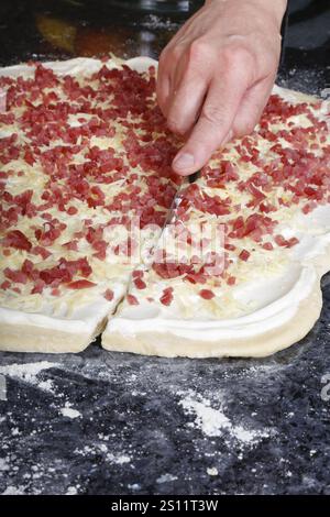 Swabian cuisine, preparation of savoury yeast plait with smoked meat, salty wreath bread, yeast yeast dough pastries, cutting raw yeast dough with bac Stock Photo