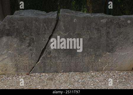 Close-up of carved letters on broken split in two large and heavy block of old weathered limestone at ancient 3rd century Roman ruins of Salona near S Stock Photo