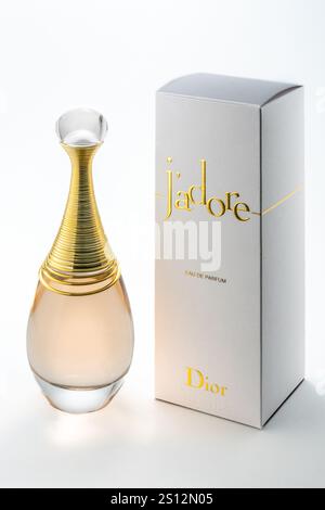 Italy - December 30, 2024: J'adore Dior perfume on white background, 100 ml ampoule of eau de parfum with packaging with gold logos and lettering Stock Photo