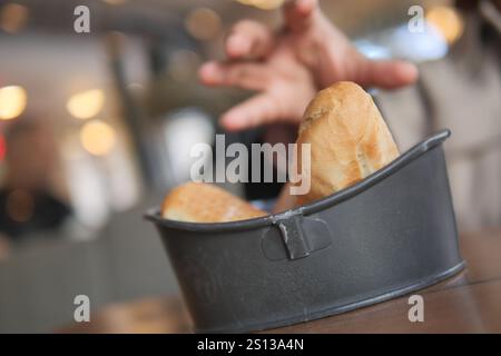 A Hand Reaching for Various Freshly Baked Breads in a Cozy Restaurant Stock Photo