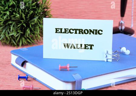 Digital financial business concept. ELECTRONIC WALLET words written on a white card standing on a business diary on an orange background. Stock Photo