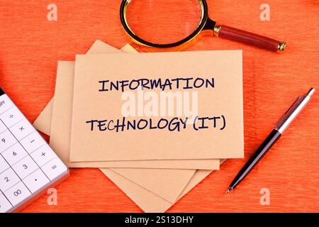 Startup office or people teamwork concept. INFORMATION TECHNOLOGY (IT) it is written on a postal envelope on an orange background, top view. Stock Photo