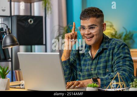 Eureka. Thoughtful inspired Indian man working on laptop make gesture raises finger came up with creative plan feels excited with good idea inspiration motivation, question at home office. Lifestyle Stock Photo