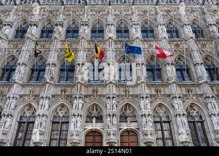 Richly decorated facade of the Town hall in Leuven, with consoles, sculptures and flags of Belgium, Europe and some provinces of Belgium Stock Photo