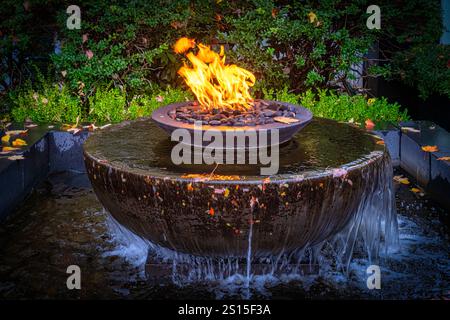 Mesmerizing balance of fire and water, this modern fountain radiates warmth and tranquility amidst a lush garden setting. Stock Photo