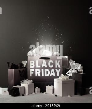 Black and white shopping bags are on a table with the word black friday spelled out on a bag for a sale savings message. Stock Photo