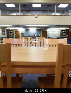 A library desk in a room with bookshelves for a study or education message. Stock Photo