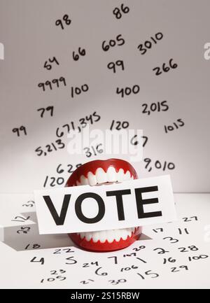 A mouth is holding the text vote in the mouth with numbers on a white wall for a conceptual voter concept for an election. Stock Photo