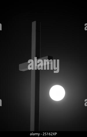 Church cross in front of the Super Hunter's Moon on October 17, 2024 which is the brightest moon of 2024, vertical Stock Photo
