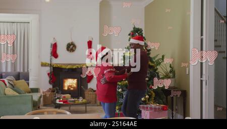 Image of christmas greetings text over african american couple dancing at christmas Stock Photo