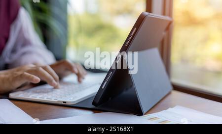 Female hands typing on tablet keyboard on wood desk at office, Technology, Business concept, Business woman analyze the graph of the company performan Stock Photo