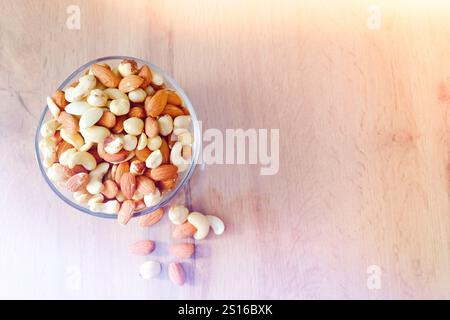 Cashews, peanuts and almonds on a plate. Nuts on the table in the bright rays of the sun.. Stock Photo