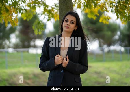 Young manager posing near a tree with green leaves in the background Stock Photo