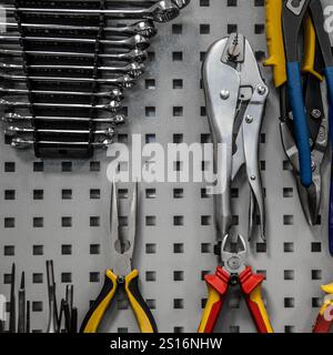 A neatly organized pegboard with various hand tools including wrenches, pliers, and locking pliers, ideal for a workshop or garage setting. Stock Photo