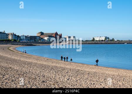 A lovely sunny morning in Morecambe on the coast of Lancashire in Northwest England. Tourists walking on the beach at low tide. Stock Photo