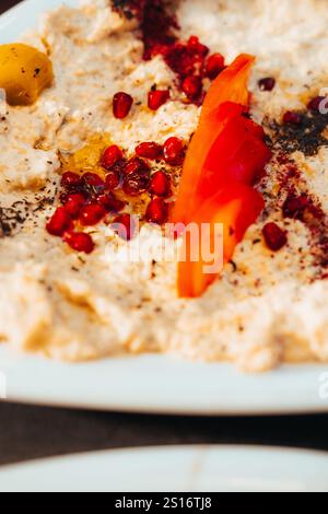 Close-Up of Creamy Hummus with Pomegranate and Tomato Garnish Stock Photo