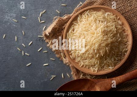 close-up of raw basmati rice grains on black textured table top surface, creamy white color grainy food taken straight from above with copy space Stock Photo