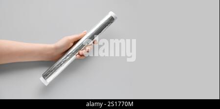 Hand holding aluminium foil roll on grey background with space for text, top view Stock Photo