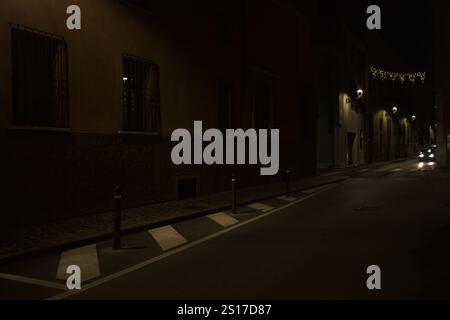 Street with a few hanging decorative lights in an italian town at night Stock Photo