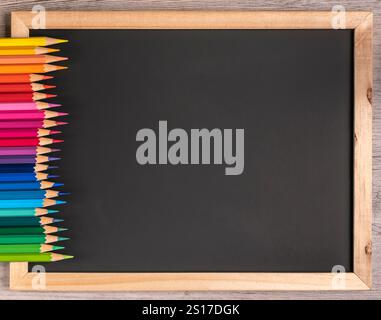 Sharp colored pencils arranged orderly on a black board with copy space. Close up, school - office supply. Stock Photo