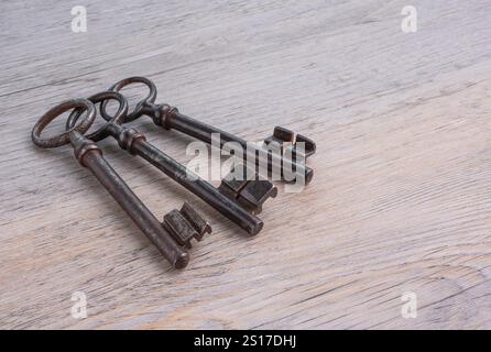 Old, rusty, iron keys on a wooden table. Stock Photo