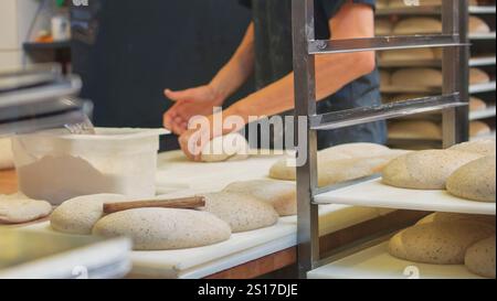 Baker hands kneading and forming the dough in the local bakery house. Small local businesses preparing flour products for sale. Stock Photo