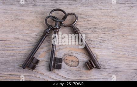 Old, rusty, iron keys on a wooden table. View from above. Stock Photo