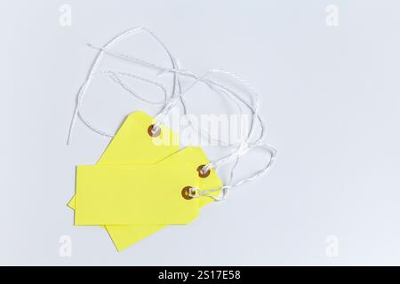 Blank yellow labels on strings on a white surface Stock Photo