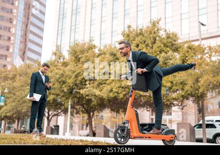 Businessman's electric scooter sparks curiosity and conversation. Funny crazy businessman on scooter represents a modern, urban lifestyle. Business ma Stock Photo