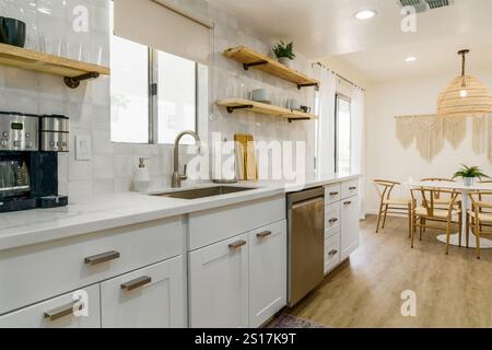 Modern kitchen with white cabinets, stainless steel appliances, and light wood flooring. Stock Photo