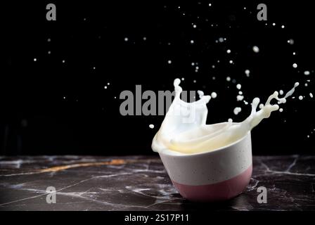 Milk Splash from the bowl on a black background. Dairy concept. No-dairy vegan plant milk splashes in bowl. Copy space. Stock Photo