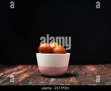 Gulab Jamun levitation on dark background. Traditional oriental food concept. Indian sweet snacks. Top view, flat lay, copy space Stock Photo