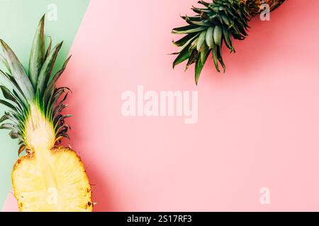 Fresh pineapple half and green leaves styled on pink and green pastel background. Top view, flat lay, copy space. Stock Photo