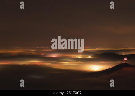 New Year's Eve fireworks 2024 on the Breitenstein, Swabian Alb near Ochsenwang. Sea of fog in the foothills of the Alb. View of the Drei Kaiserberge n Stock Photo