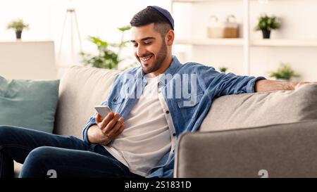 Closeup of smiling jewish man using smartphone at home Stock Photo
