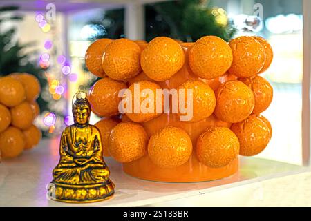 Buda figurine on a background of orange oranges in the interior Stock Photo