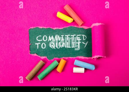 Committed to Quality. Text under torn purple paper on a green chalkboard. Stock Photo
