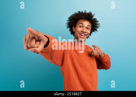 Young man with curly hair joyfully points at the camera Stock Photo