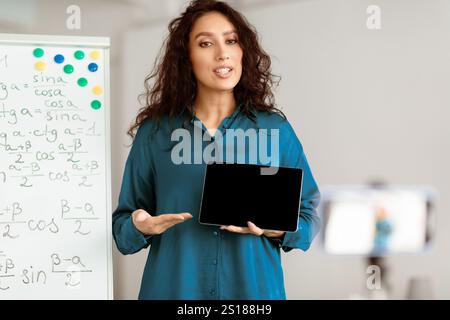Lady teacher explaining math online showing tablet to students Stock Photo