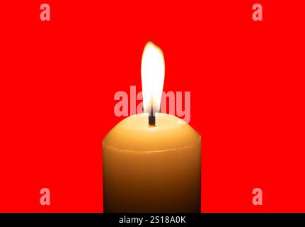 A single burning candle flame or light glowing on a big white candle is isolated on red background with clipping path. Stock Photo