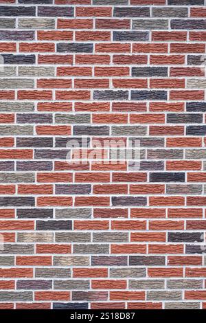 Arrangement of a random pattern of grey, black and red brick with mortar on a wall surface Stock Photo